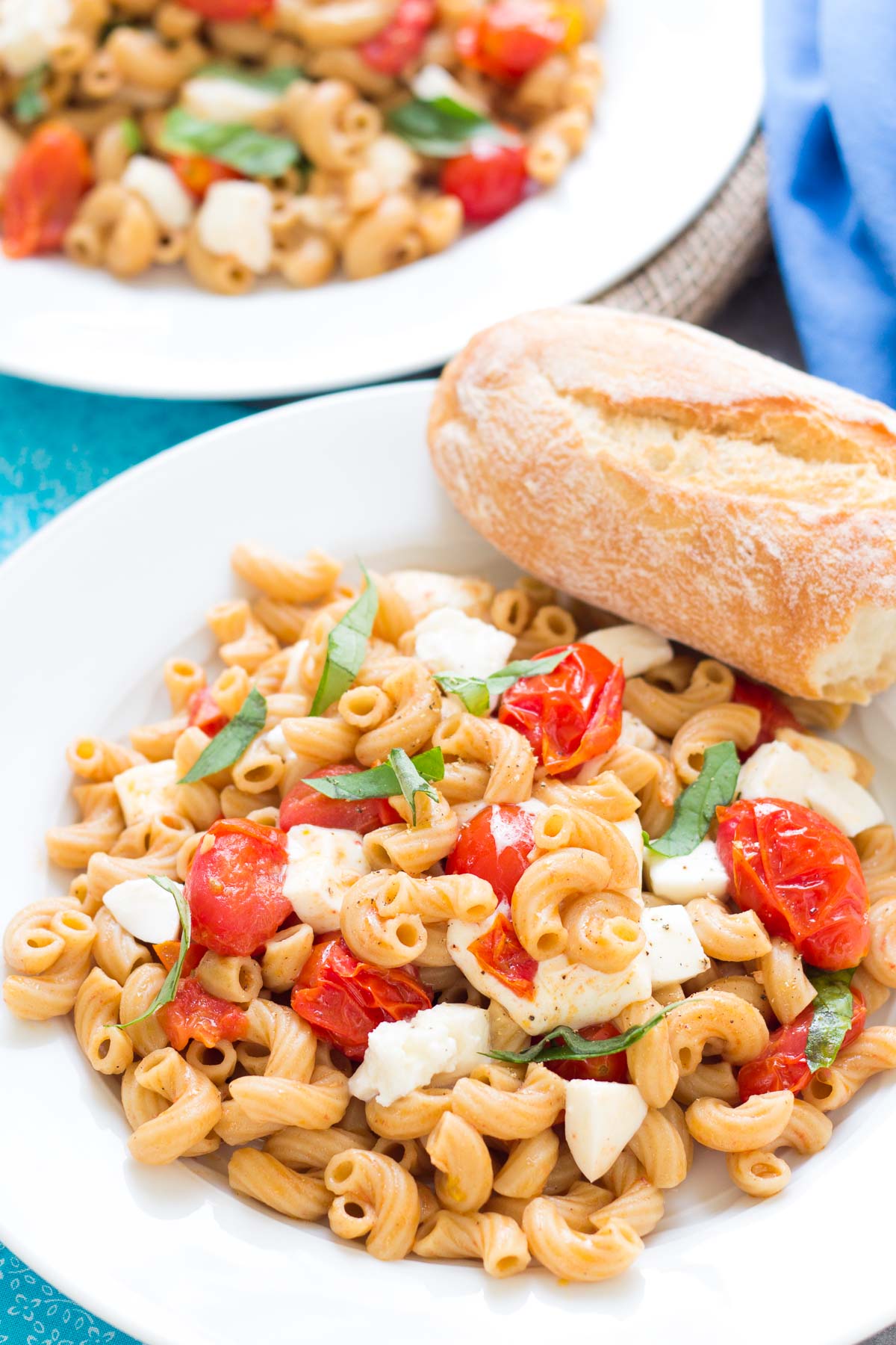 Easy caprese pasta with fresh mozzarella, tomatoes and basil, served with crusty bread.