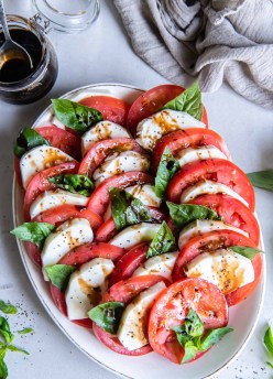 Caprese salad served on an oval plate with balsamic reduction.