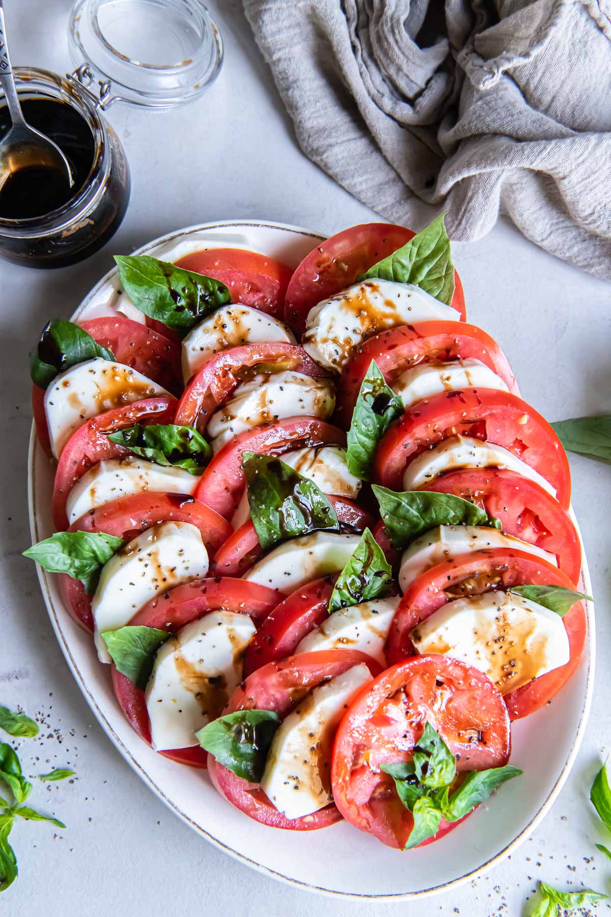Caprese salad served on an oval plate with balsamic reduction.