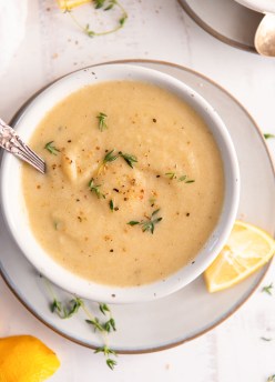 Cauliflower soup served in a bowl with a spoon and fresh thyme garnish.