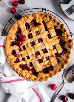 Whole baked homemade cherry pie with lattice crust.
