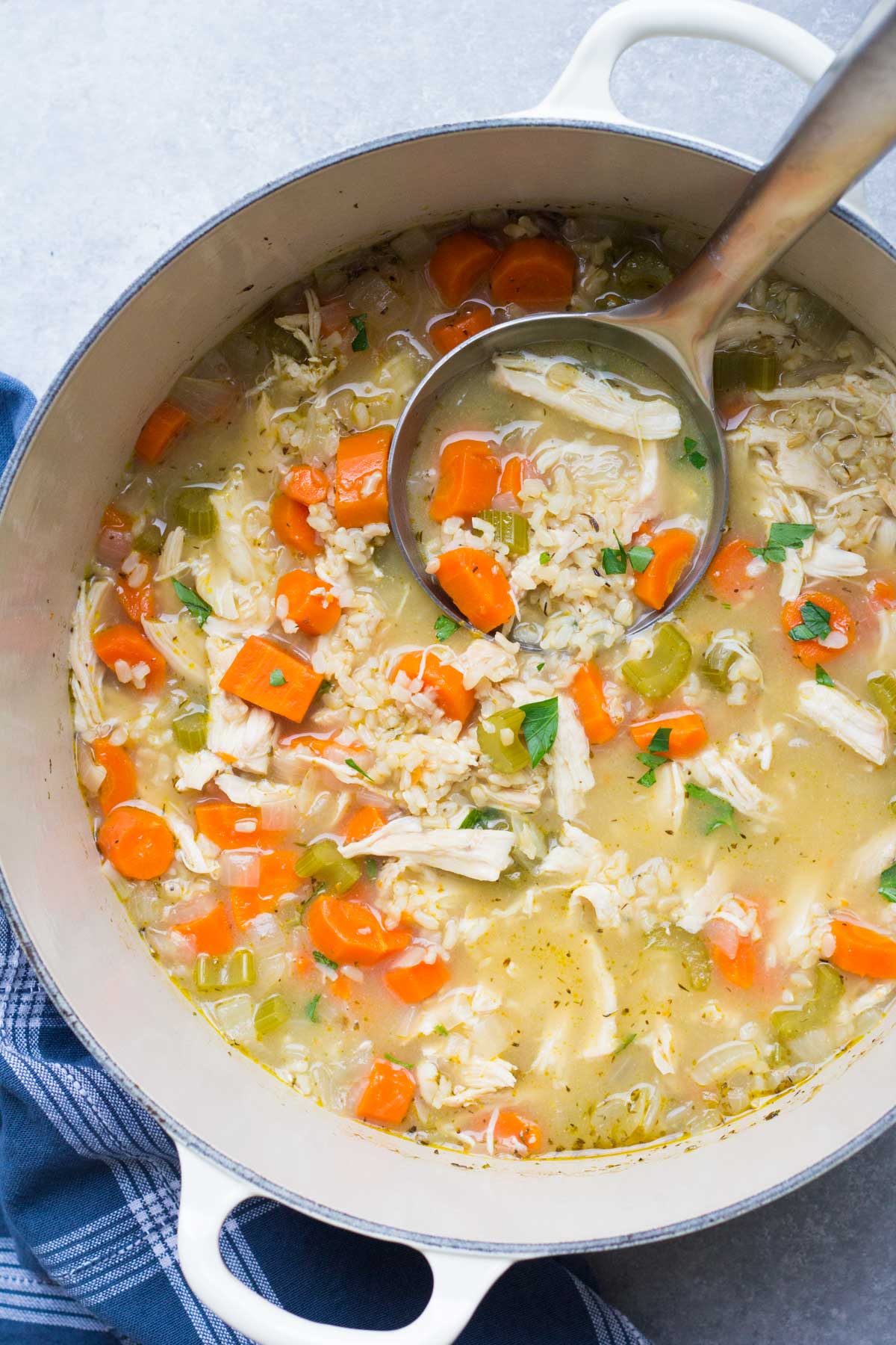 Chicken and rice soup in a Dutch oven pot with a ladle.