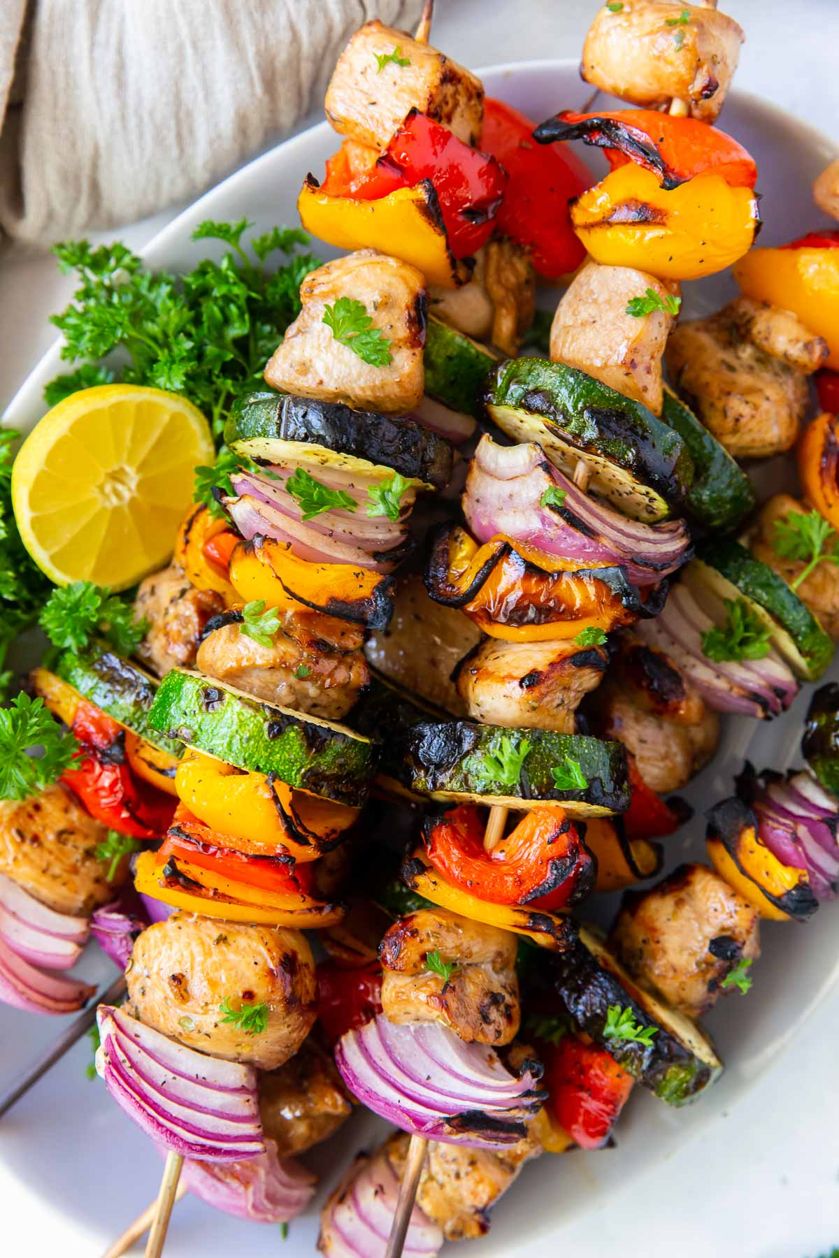 Grilled chicken kabobs with vegetables stacked on a plate.