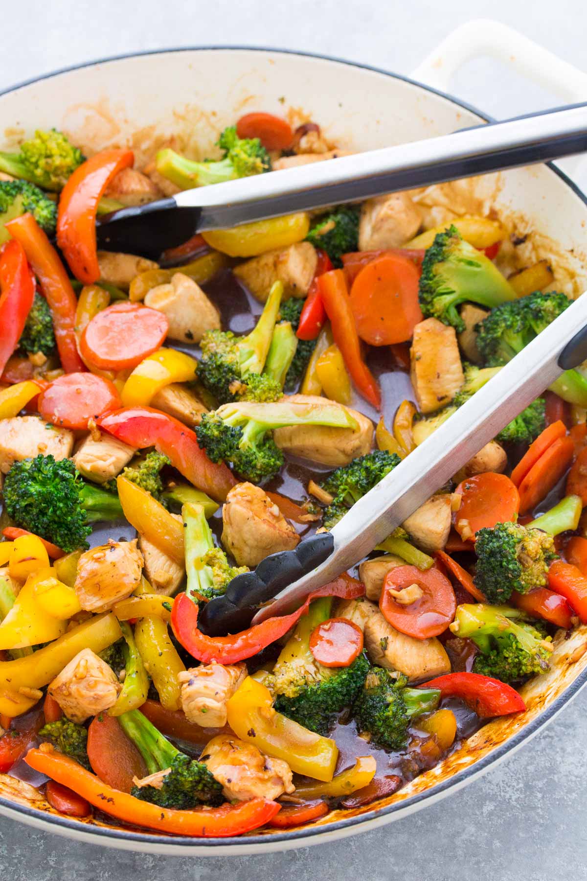 Chicken stir fry with vegetables and sauce in a large skillet.