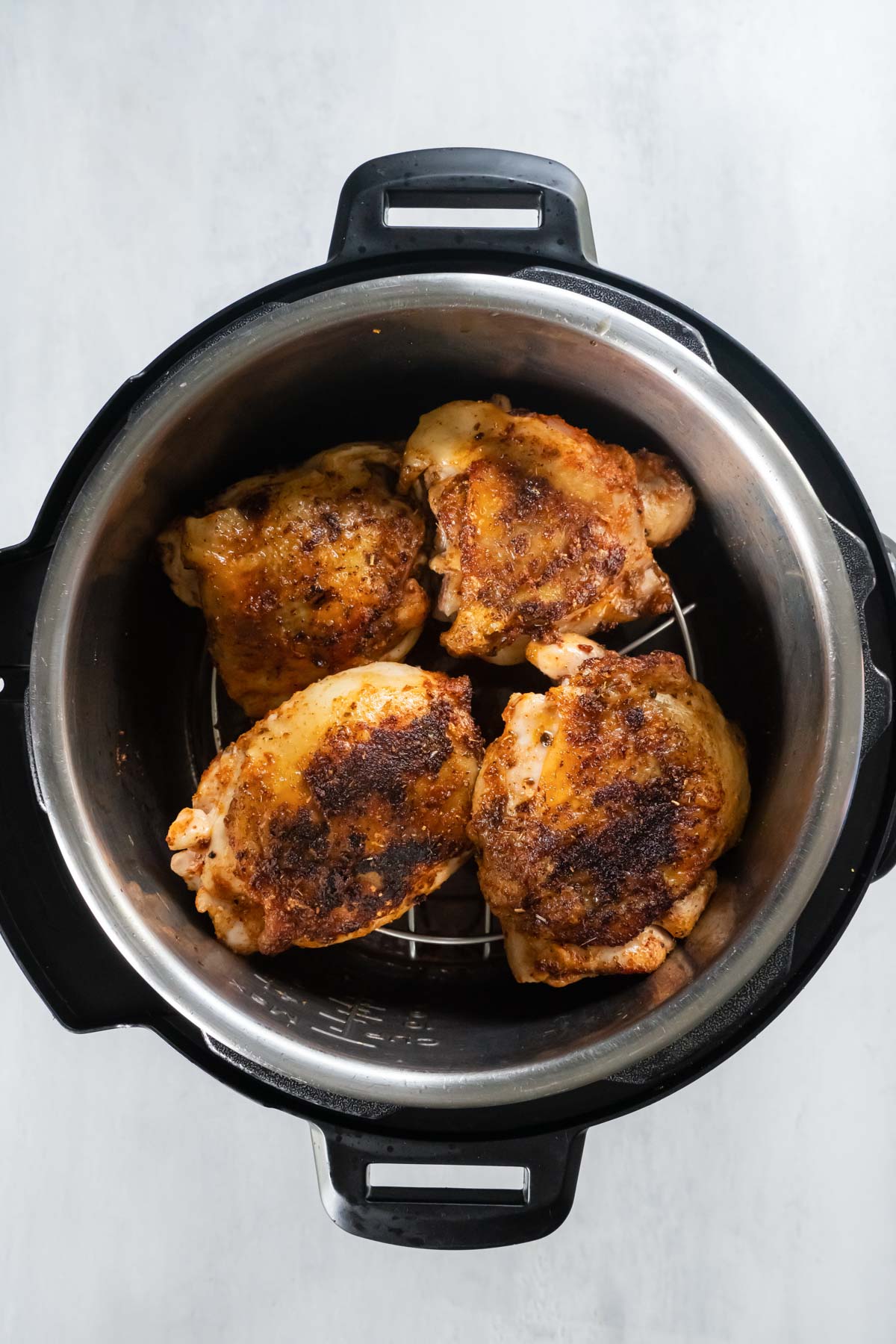 Four bone in chicken thighs on trivet in Instant Pot after pressure cooking.