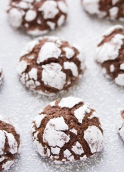 close up of chocolate crinkle cookies with powdered sugar on parchment paper