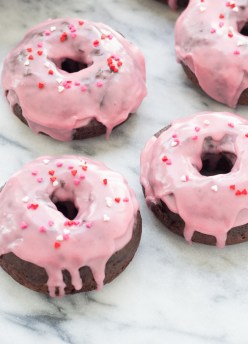 four chocolate donuts with pink glaze and sprinkles