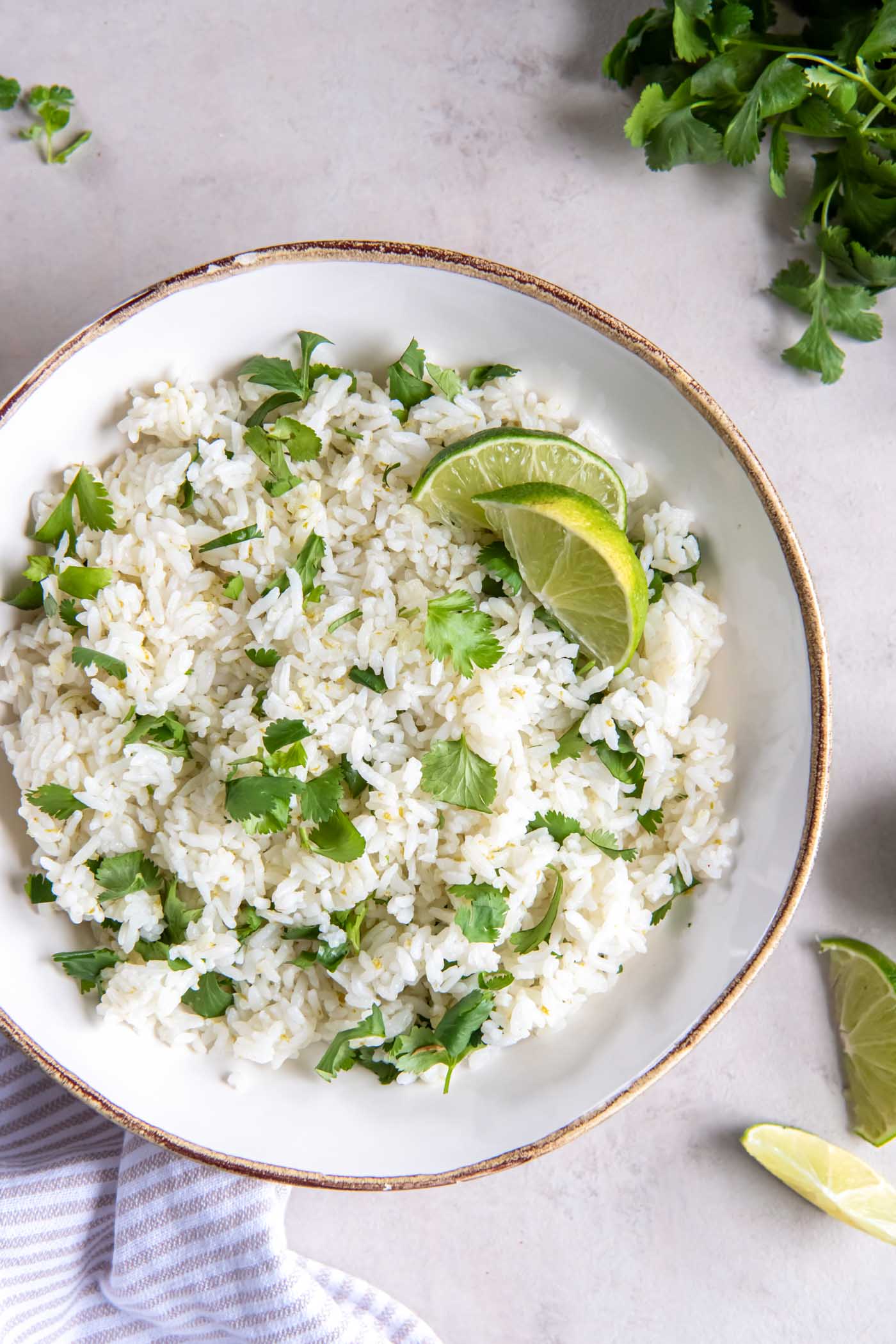 Cilantro lime rice in serving bowl garnished with lime wedges.