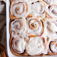 Cinnamon rolls with cream cheese icing in baking dish.