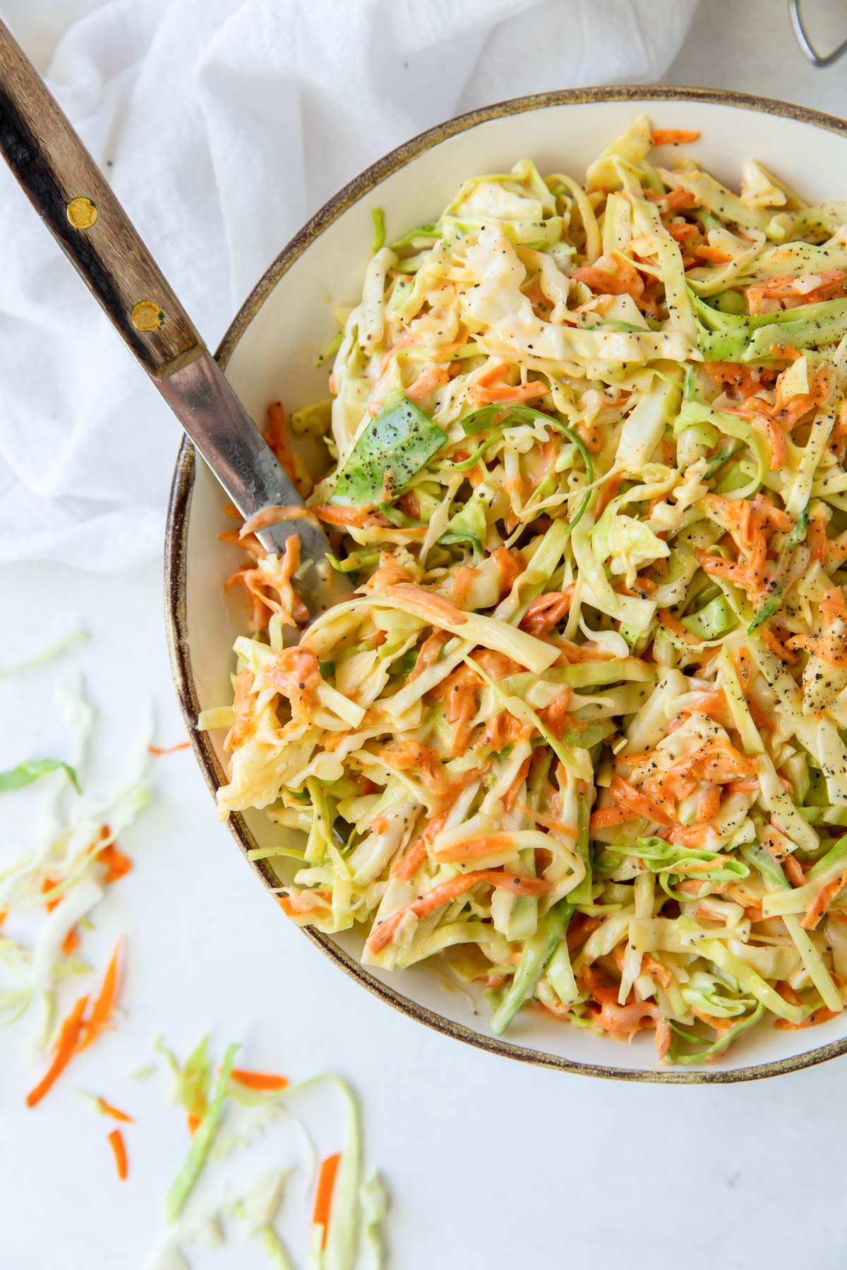 Cabbage and carrot coleslaw in a bowl with a serving spoon.
