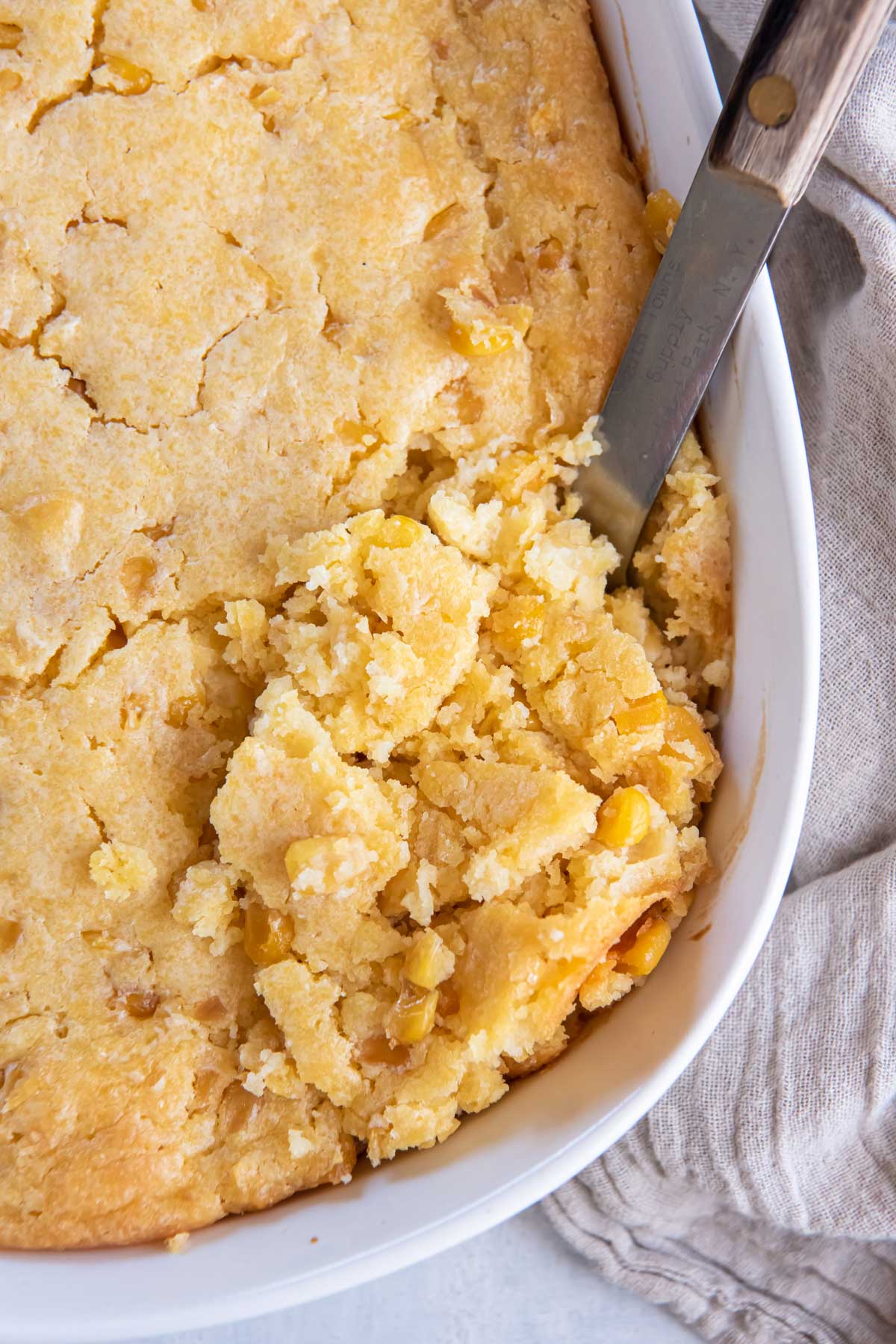 Corn casserole in baking dish with serving spoon.