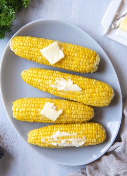 Four ears of corn on the cob served with butter.