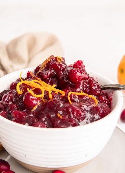 Homemade cranberry sauce with a spoon in a white serving bowl.