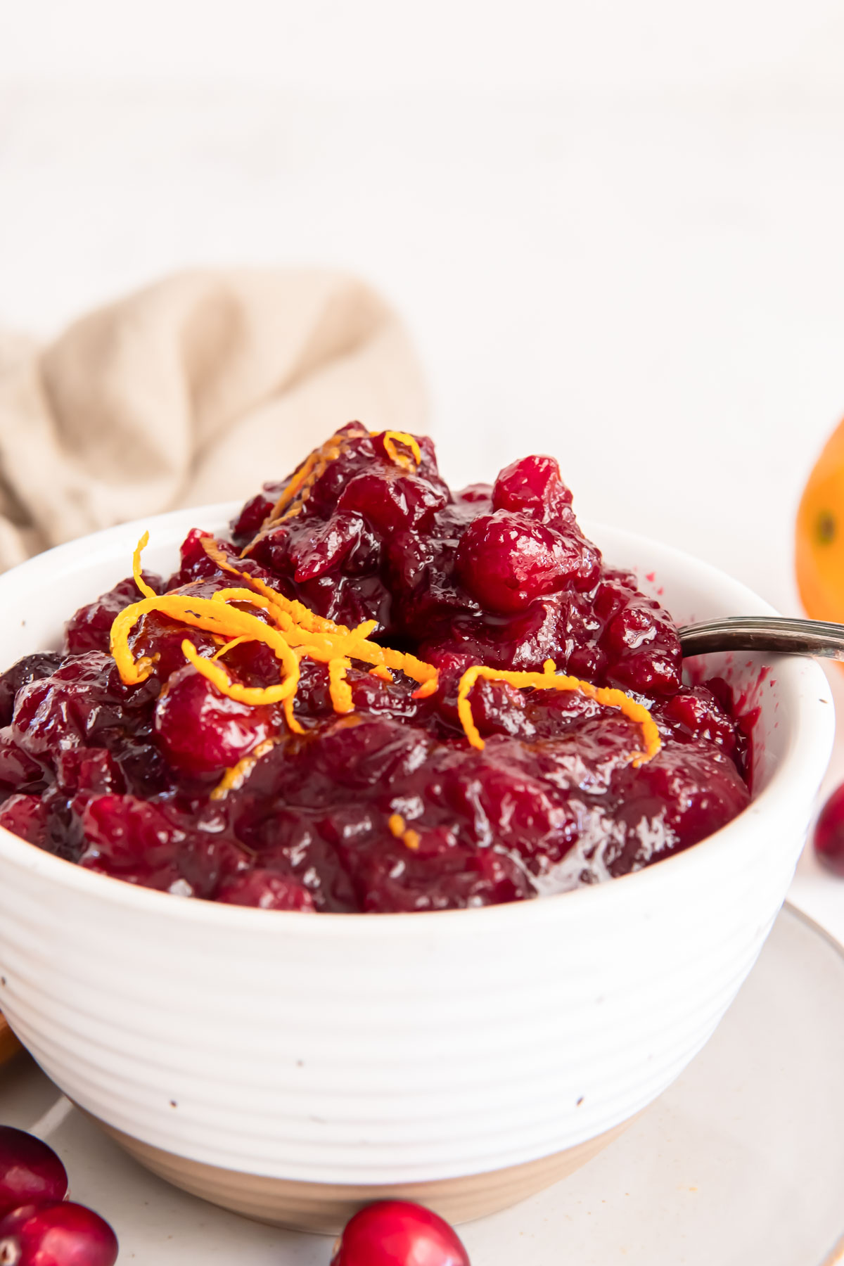 Homemade cranberry sauce with a spoon in a white serving bowl.