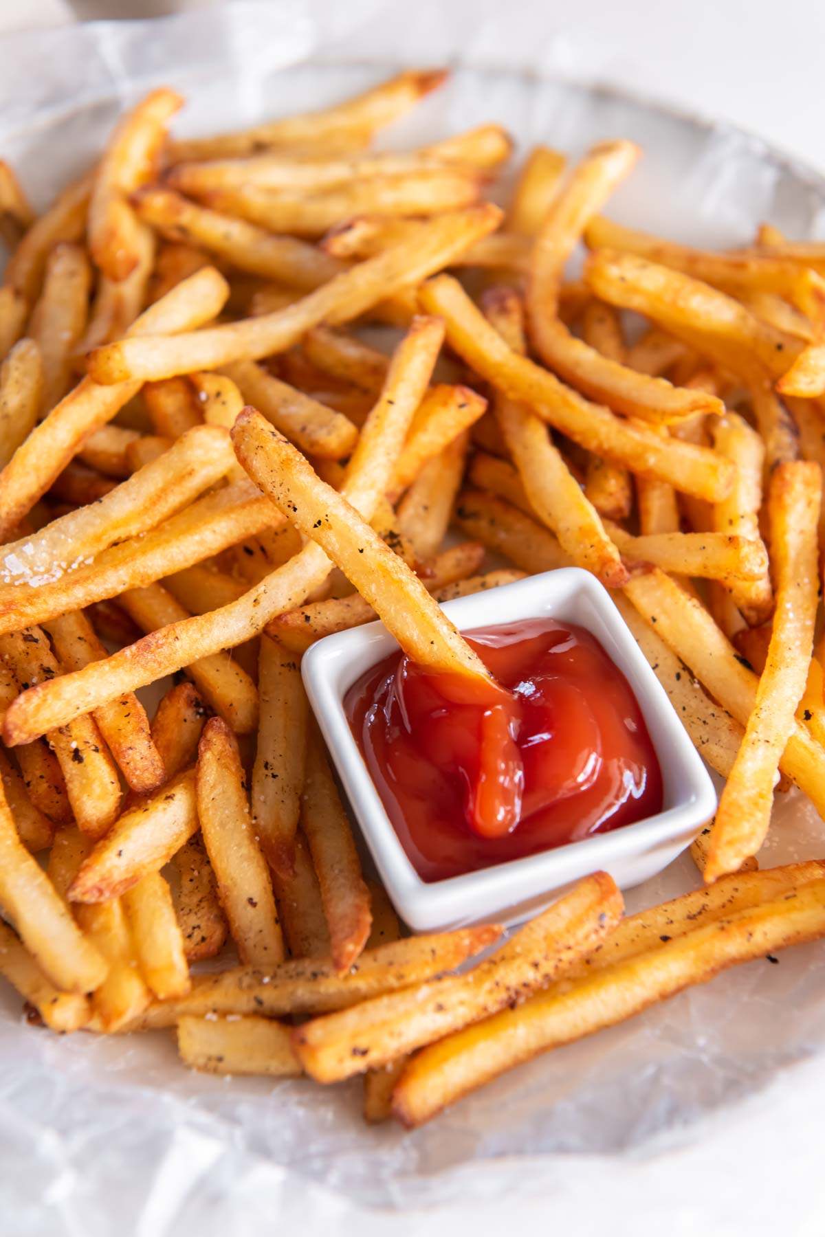 Air fried frozen french fries served with ketchup with one fry in ketchup dish.