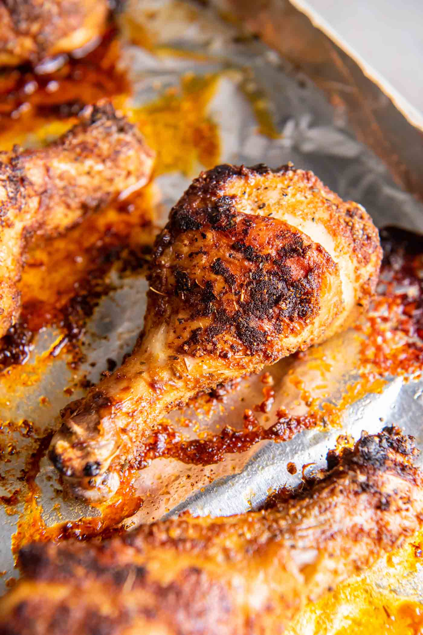 Close up of baked chicken drumstick on baking sheet.