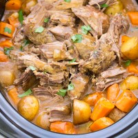 Pot roast in crock pot with potatoes, carrots and gravy.