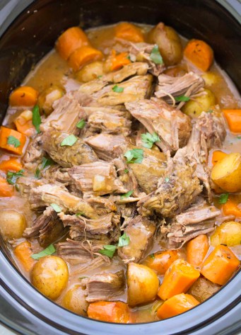 Crock pot roast shredded in a slow cooker, with potatoes, carrots and gravy.
