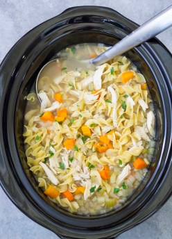Crockpot chicken noodle soup in a slow cooker with a ladle.