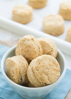 Whole wheat biscuits in a bowl with a baking sheet in the background.
