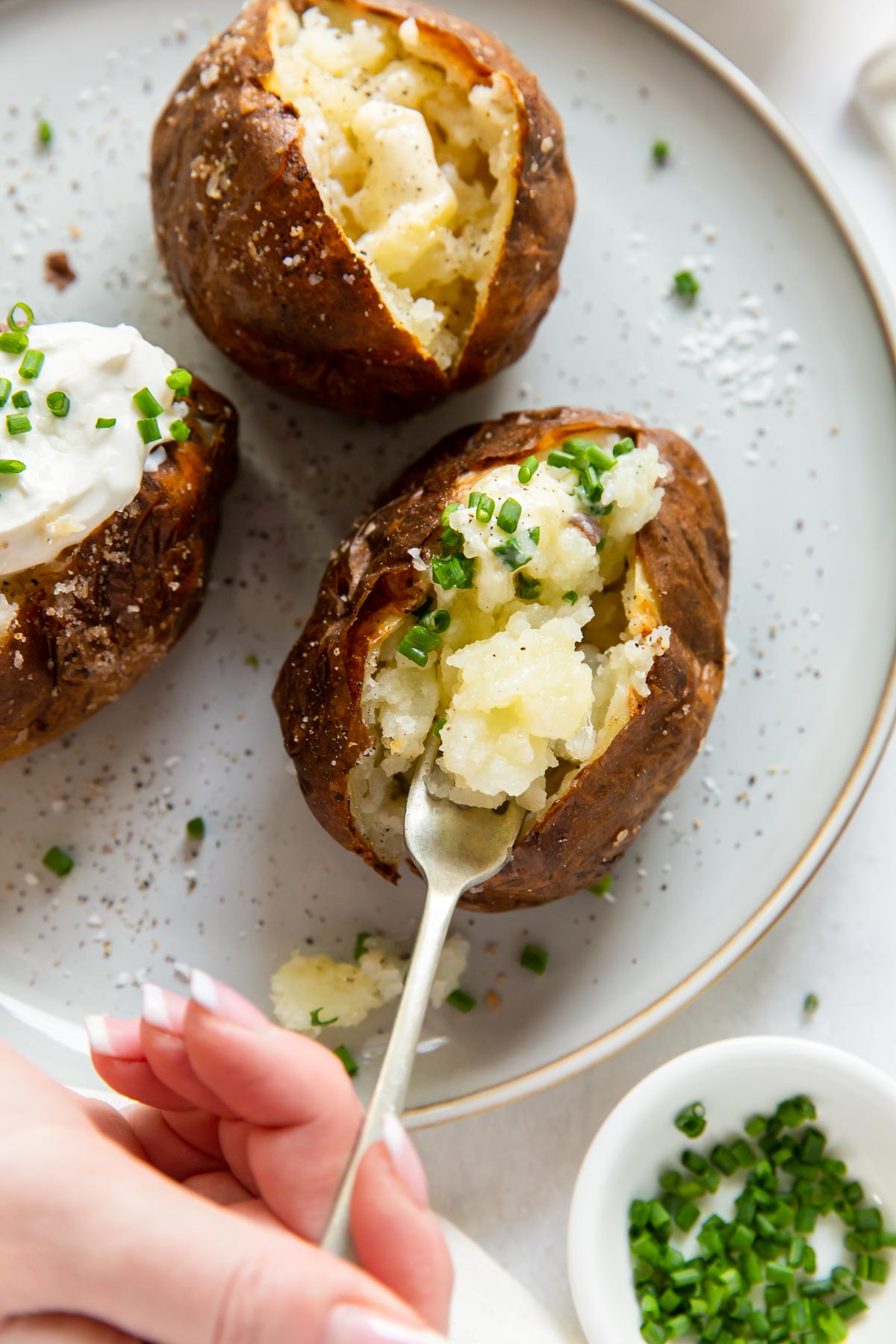 Taking a bite of baked potato with a fork.