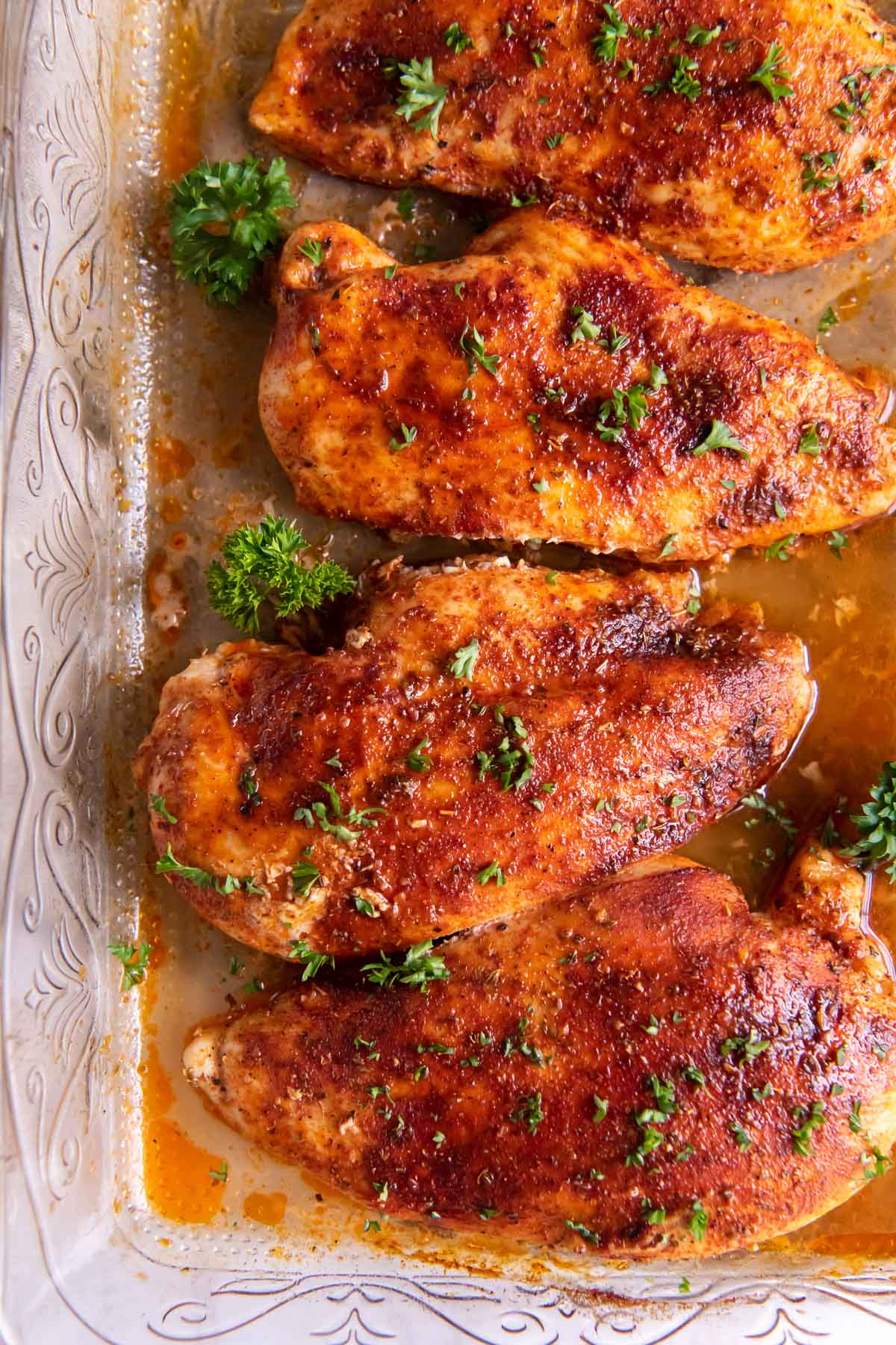 Four baked chicken breasts in a baking dish.