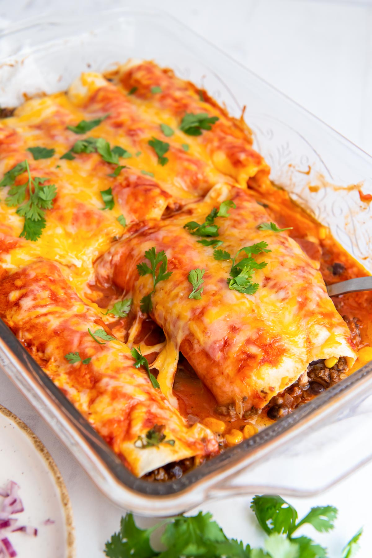 Two enchiladas on a serving spatula in baking dish.