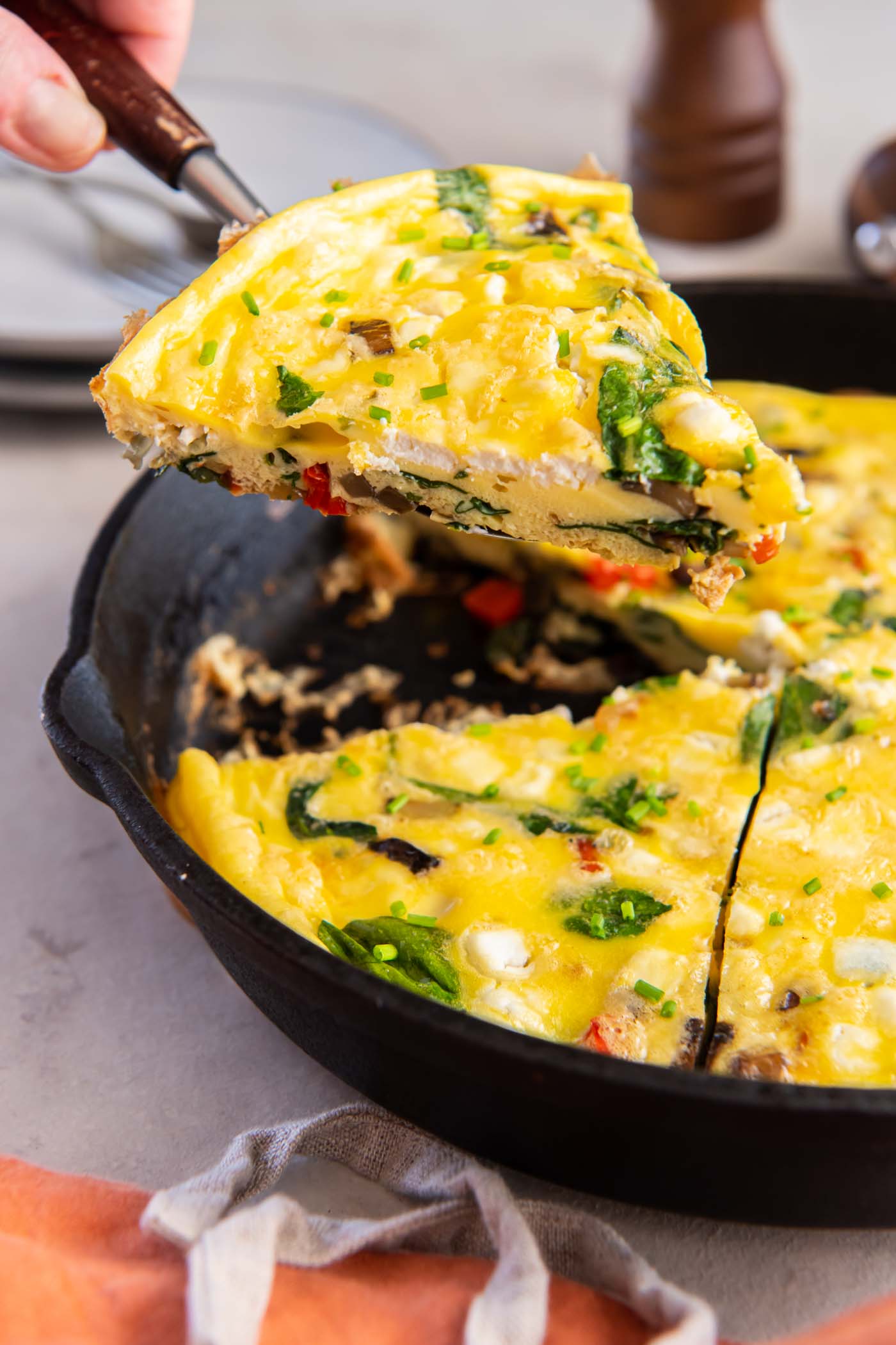 Lifting slice of frittata out of skillet with a spatula.