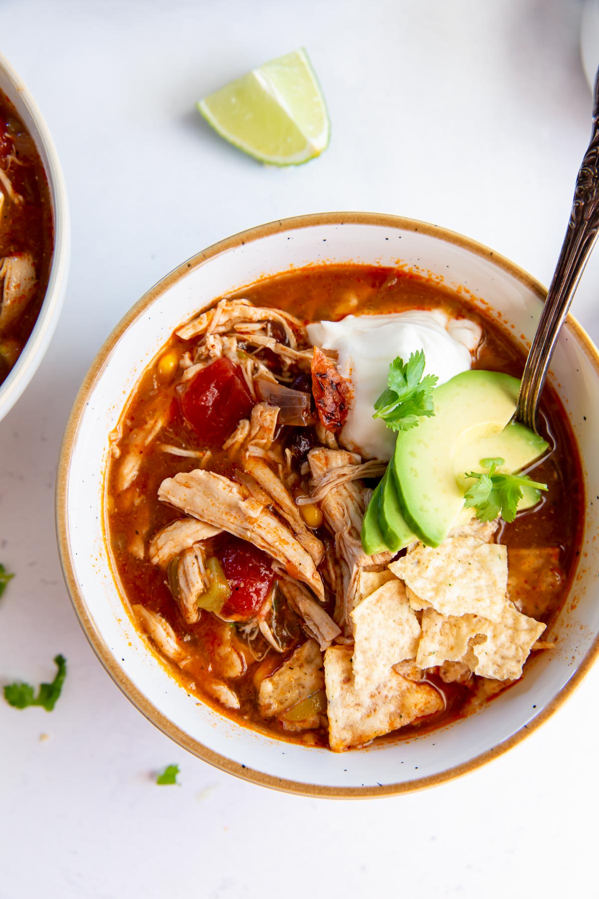 Bowl of instant pot chicken tortilla soup topped with sour cream, avocado and tortilla chips.