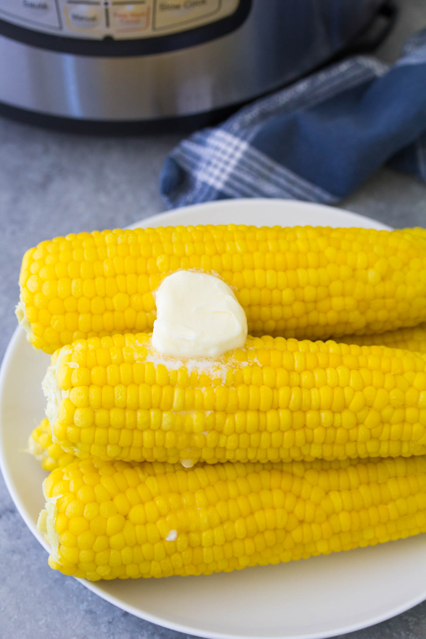 Corn on the cob on a plate with butter.