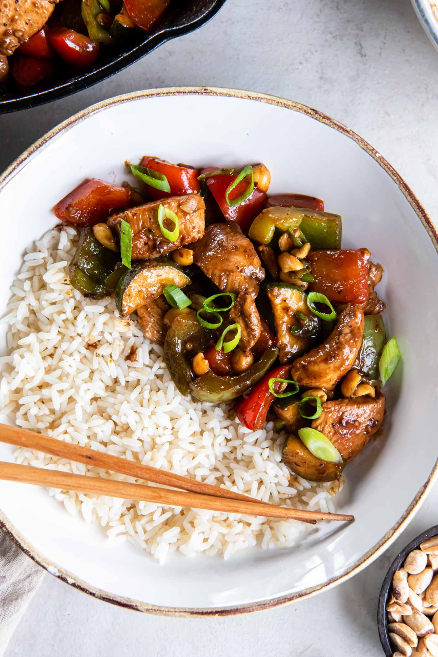 Kung pao chicken served with white rice and chopsticks.