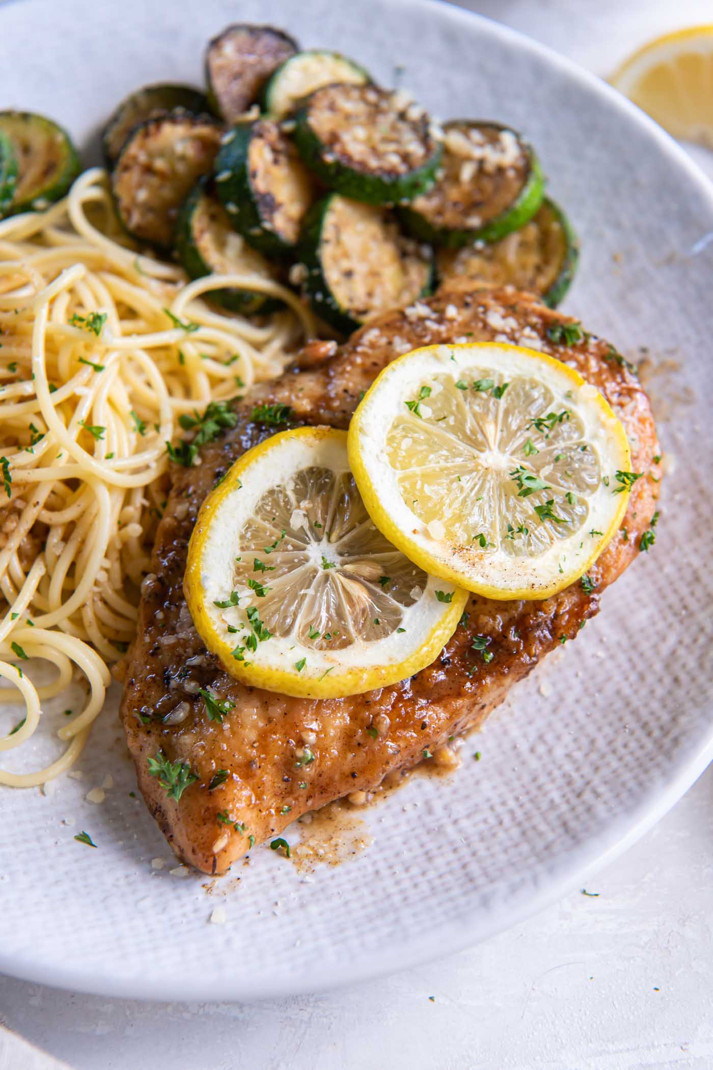 Lemon chicken served with spaghetti and sautéed zucchini.