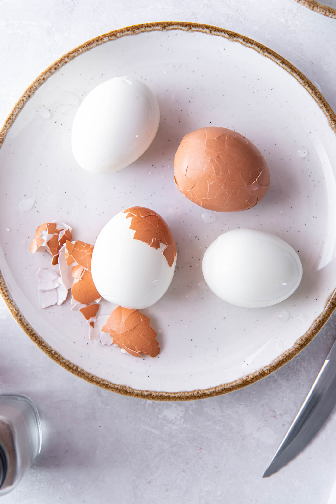 Partially peeled soft boiled eggs on a plate.