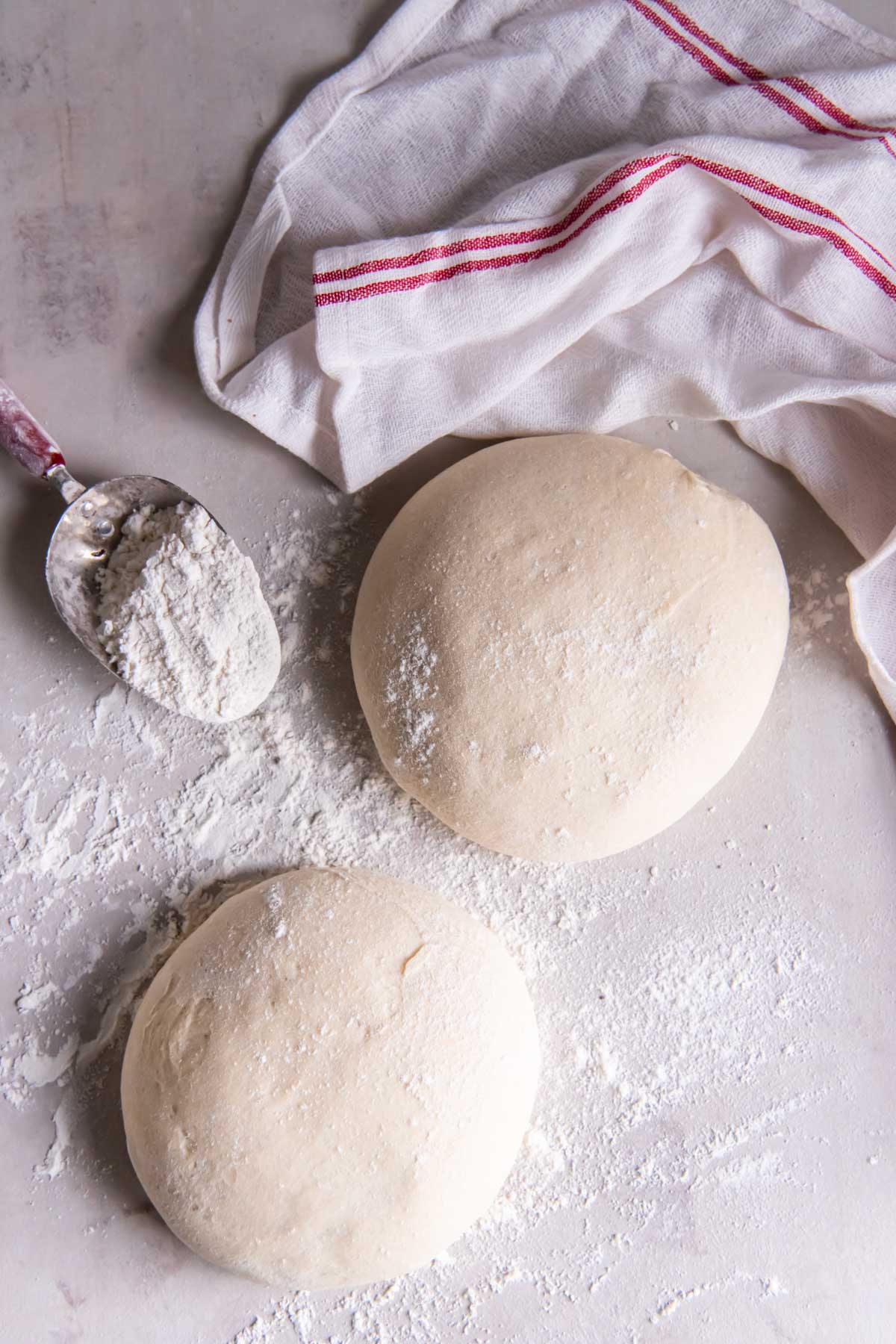 Two balls of pizza dough on a floured work surface.
