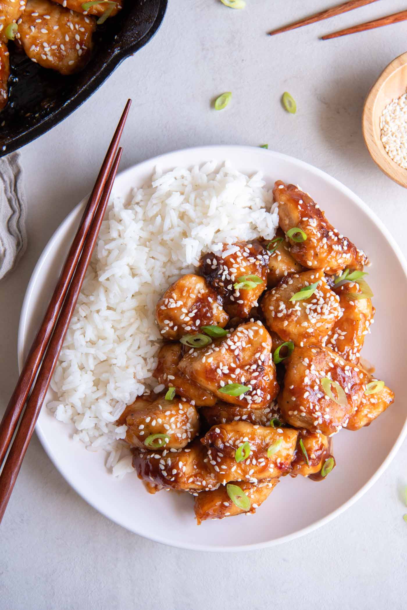 Sesame chicken served on a plate with white rice on the side.