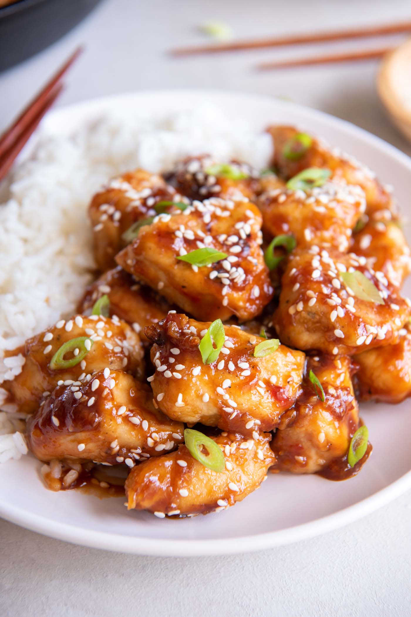 Sesame chicken served with white rice, sesame seeds and green onions.