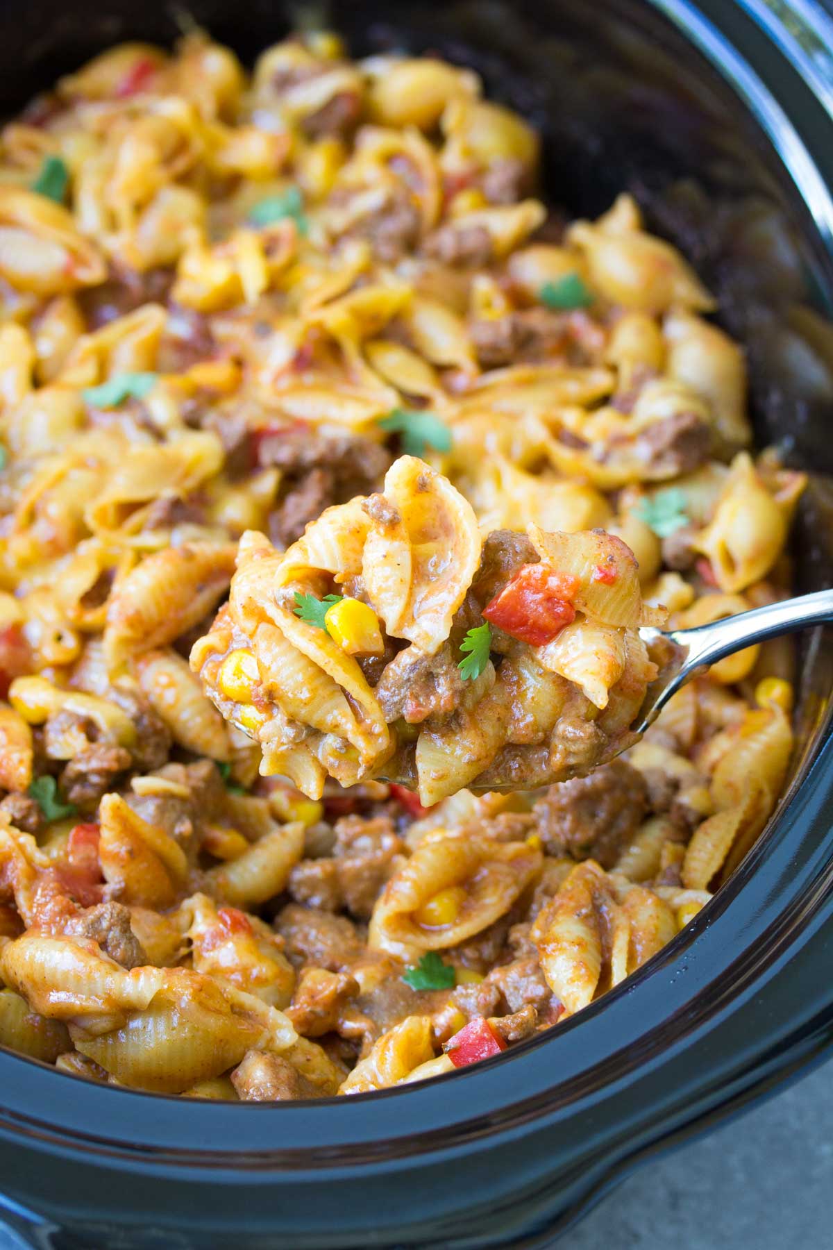 Taco pasta with serving spoon in slow cooker.