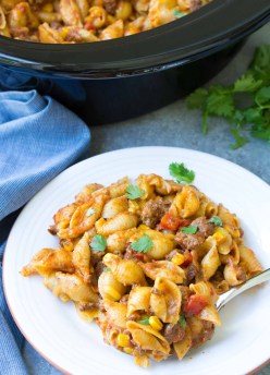 Easy Slow Cooker Taco Pasta on a plate with spoon and garnish