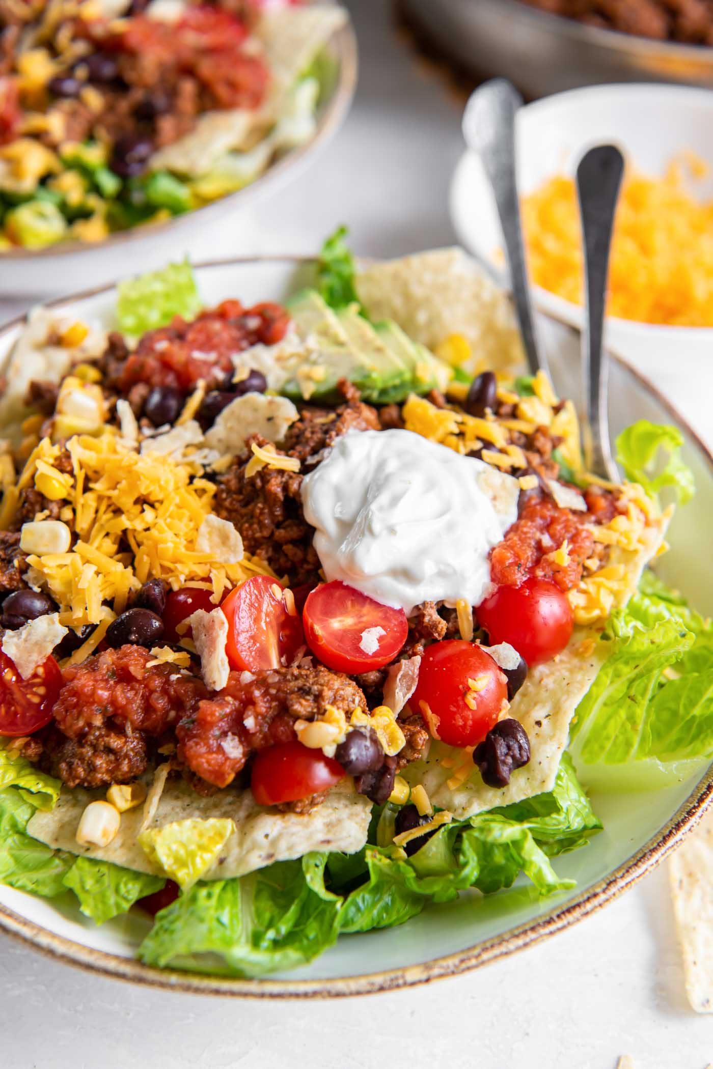 Serving of taco salad in a salad bowl with two forks.