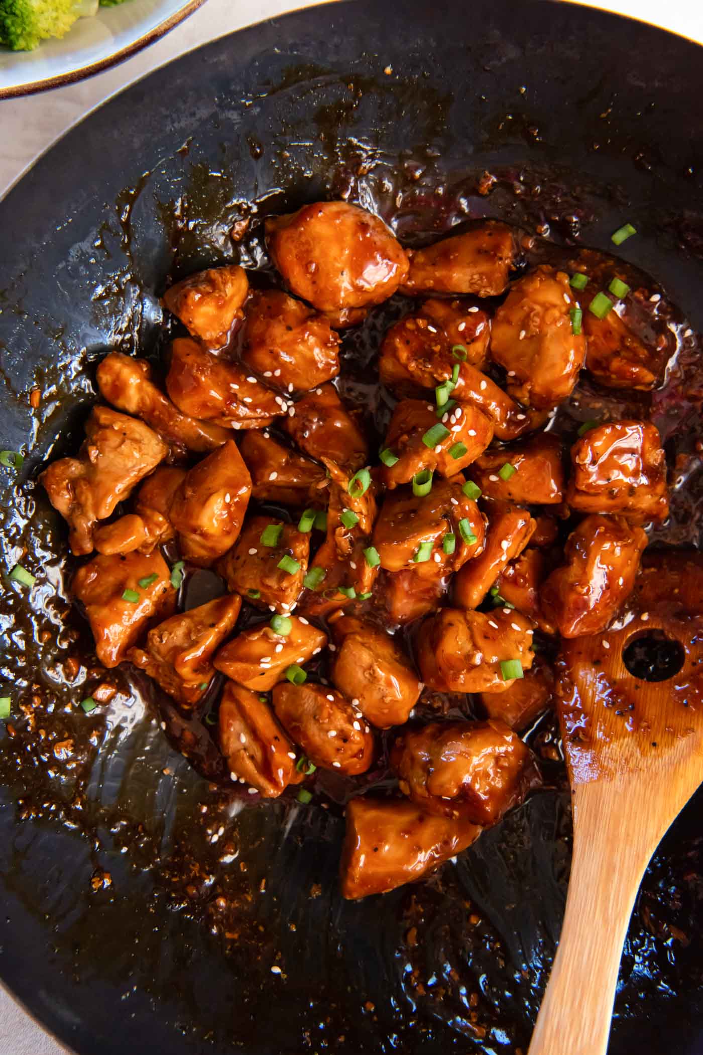 Teriyaki chicken in a skillet with a wooden spoon.