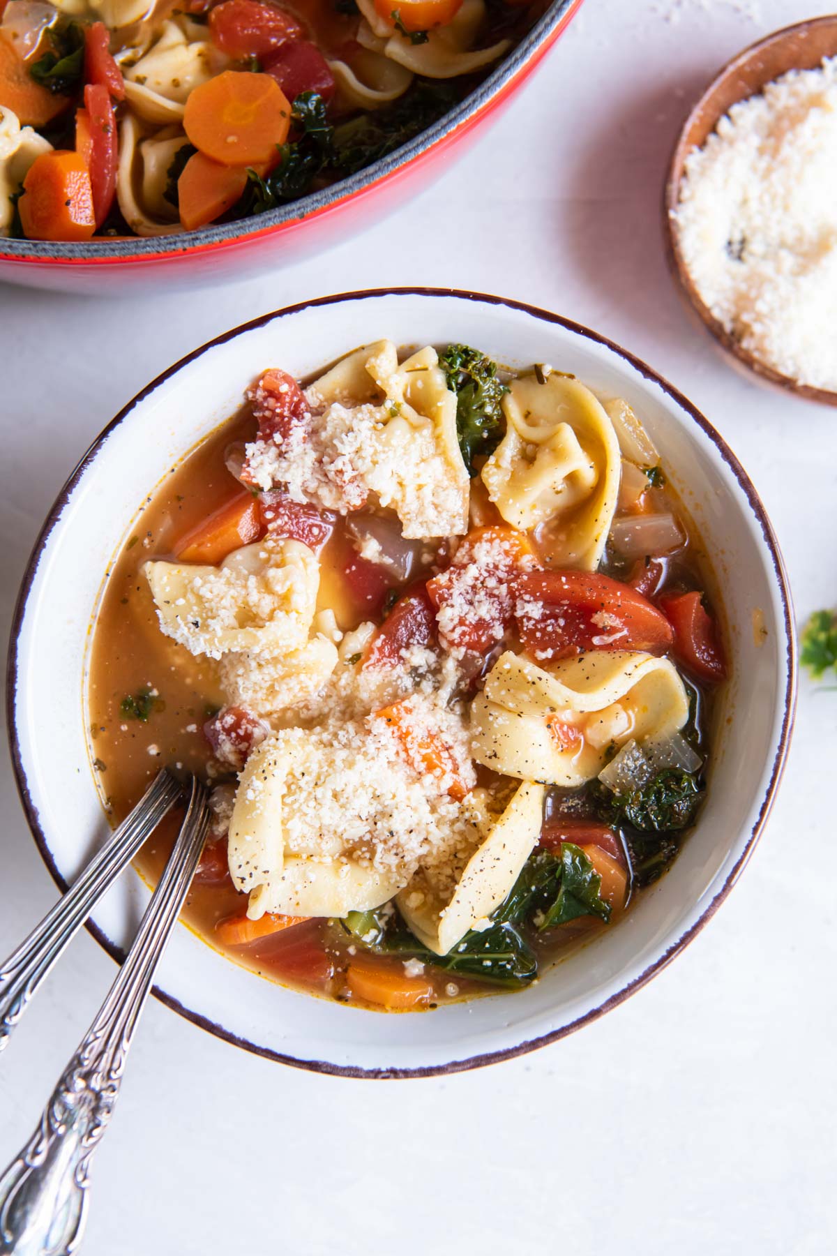 Bowl of tortellini soup with parmesan and spoon.