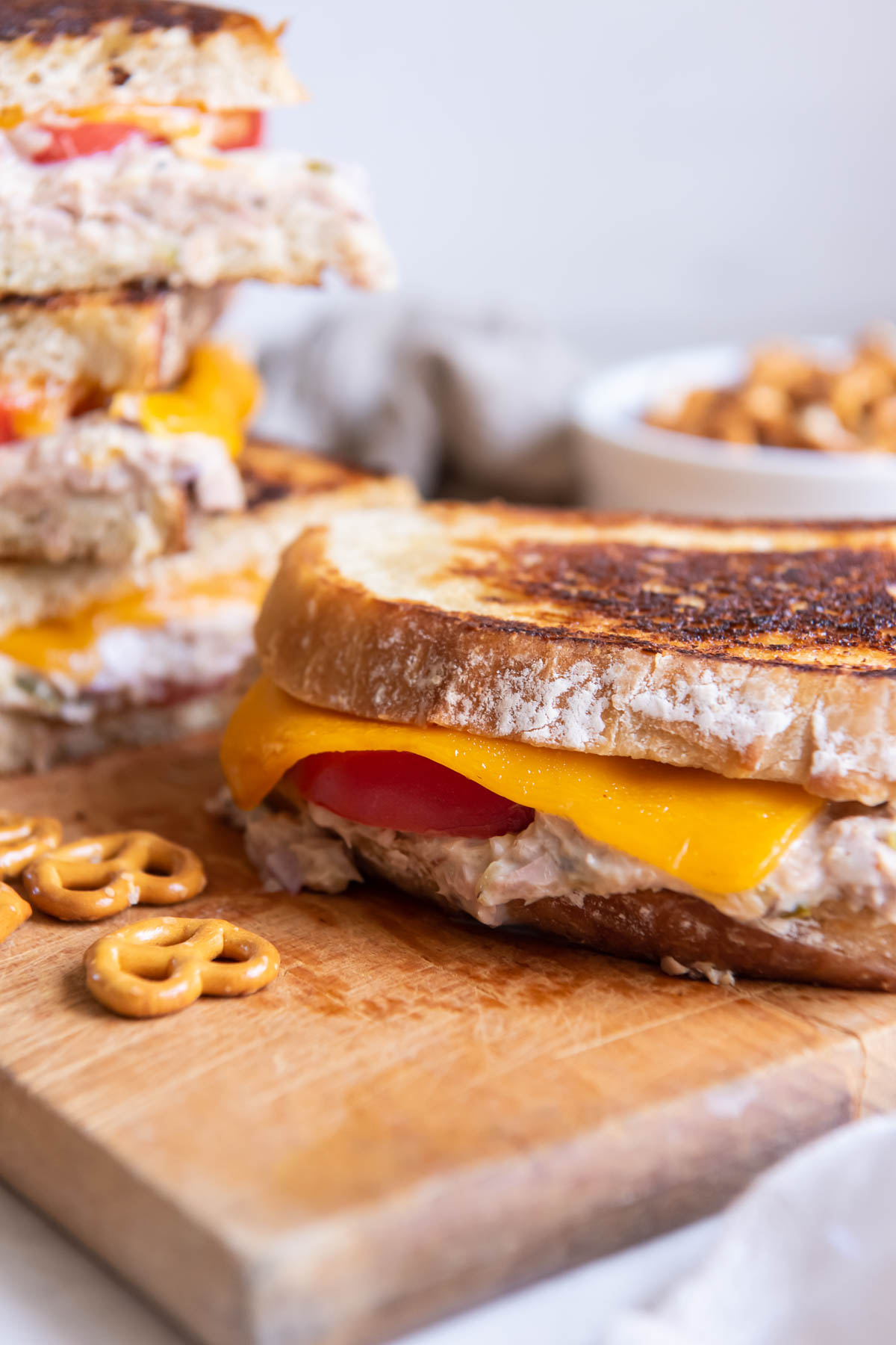 Tuna melt sandwich on a cutting board with a few pretzels on the side.