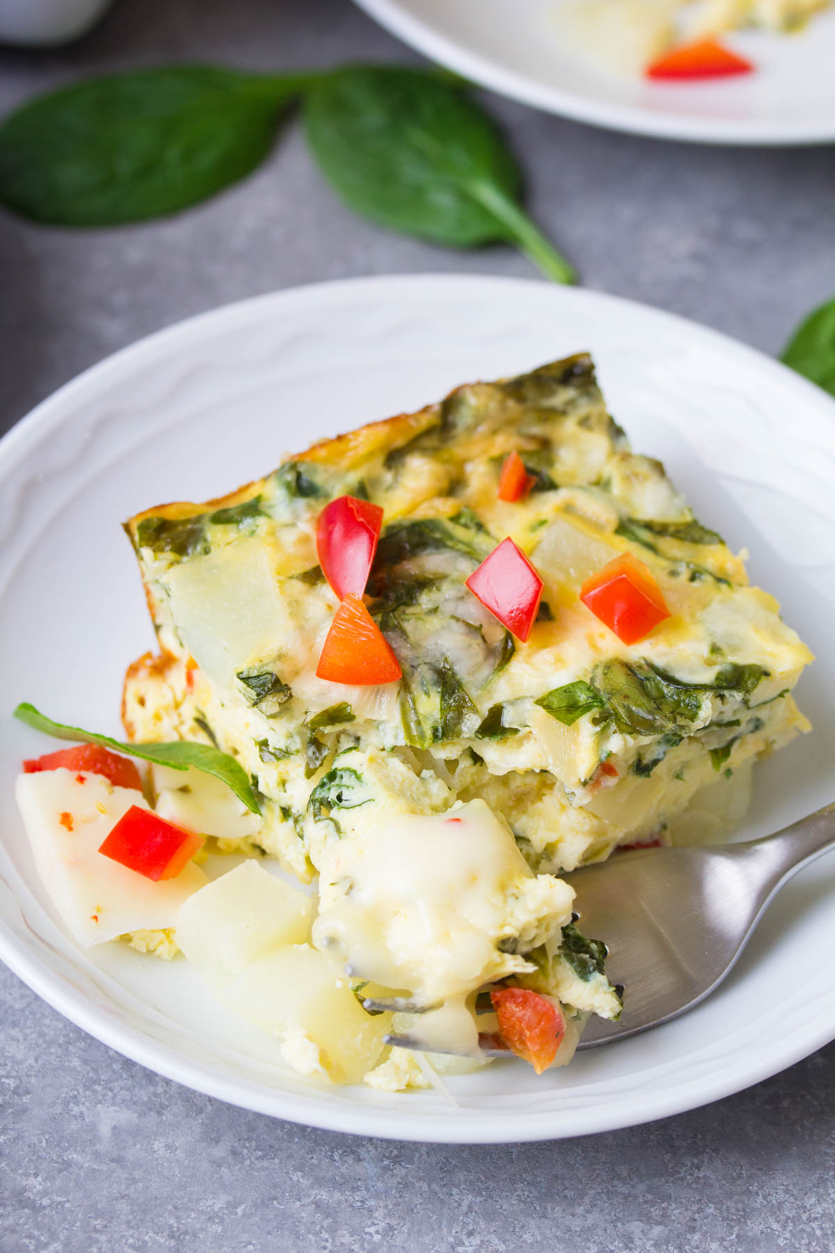 A slice of vegetarian breakfast casserole with a fork.