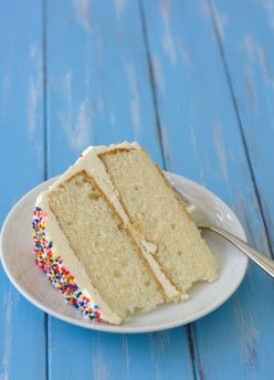 slice of white layer cake with sprinkles on a plate