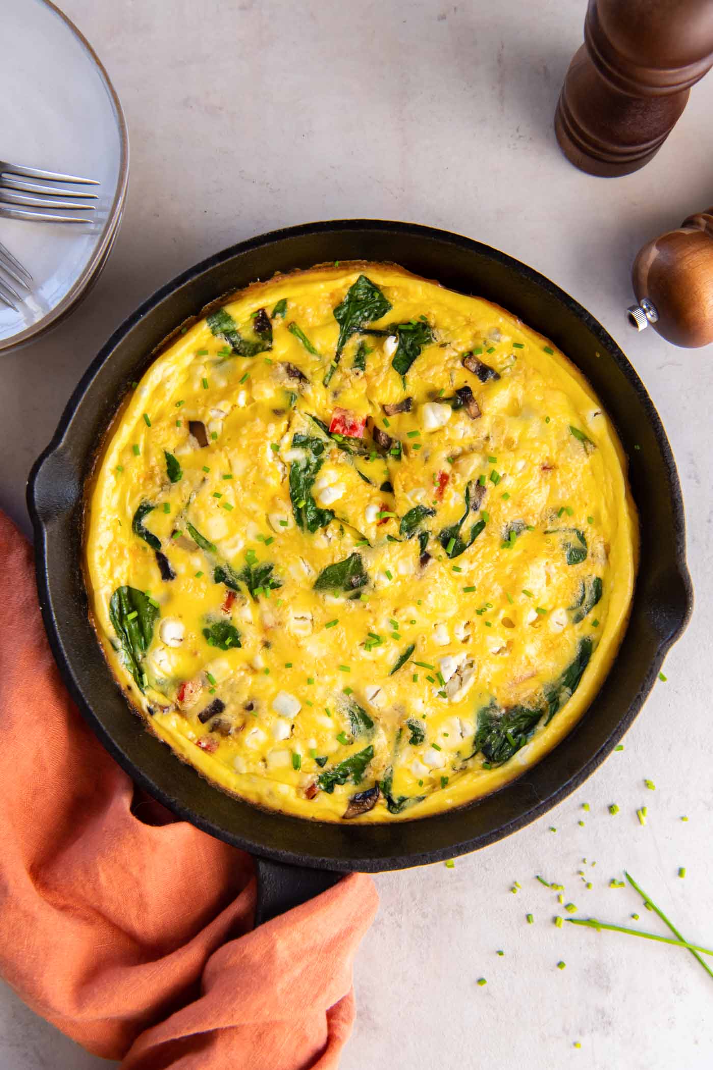 Baked frittata with spinach, bell pepper, mushrooms, onion and goat cheese in a cast iron skillet.