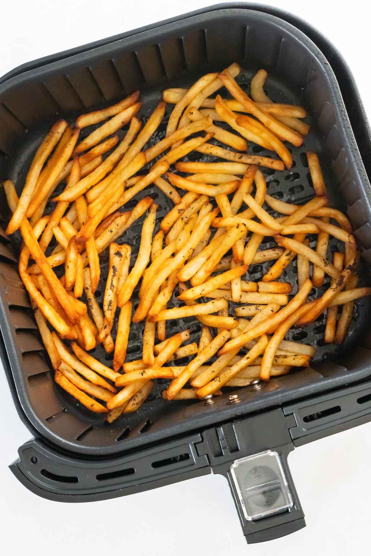 Cooked frozen french fries in air fryer basket.