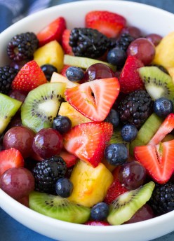 Fresh fruit salad with honey lime dressing in a white bowl.