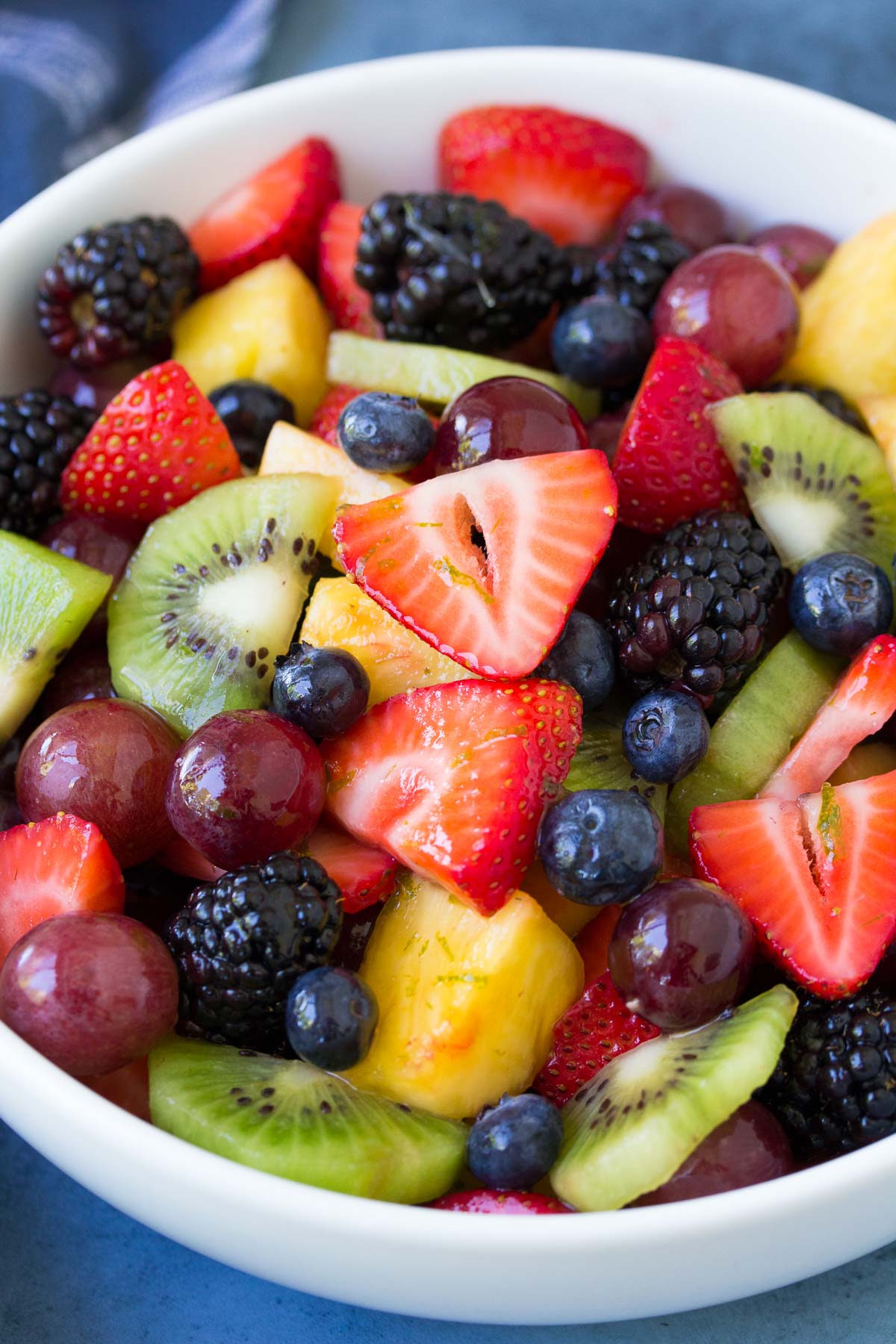 Fresh fruit salad with honey lime dressing in a white bowl.