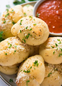 garlic knots stacked on a plate, with marinara sauce