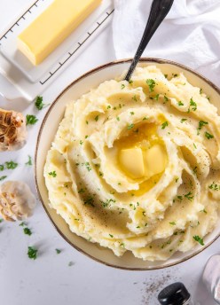 garlic mashed potatoes in a serving bowl topped with butter
